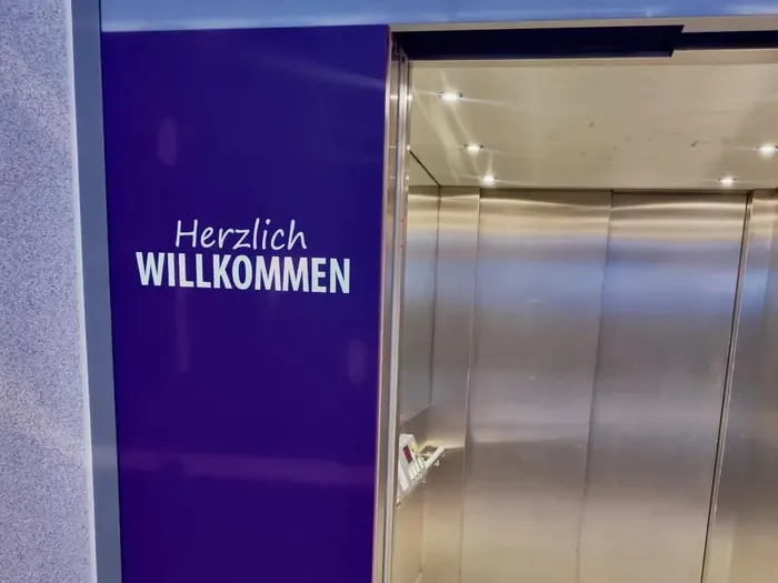 Lift sa ljubičastim zidom i natpisima Herzlich willkommen (dobrodošao)